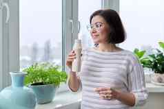 中年女人喝牛奶喝液体酸奶瓶首页窗口