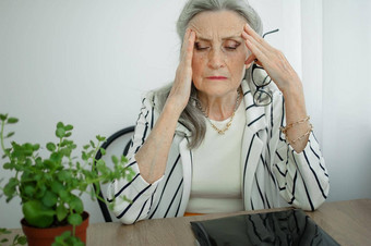 累了高级灰色头发的女商人条纹夹克眼镜工作办公室坐着桌子上感觉坏由于更年期更年期救援概念