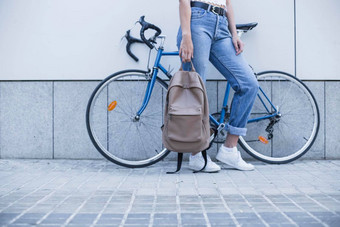 低部分年轻的女人站自行车持有背包