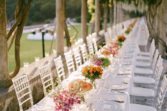 婚礼晚餐表格接待长婚礼表格的角度来看花束黄色的橙色粉红色的玫瑰表玻璃椅子拉奥蒂芙尼使透明的塑料