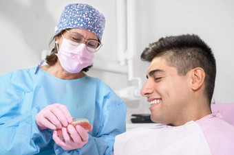 牙齿矫正医师持有看不见的护圈牙齿对齐诊所显示病人现代牙科技术可移动的透明的塑料调整器隐适美好处