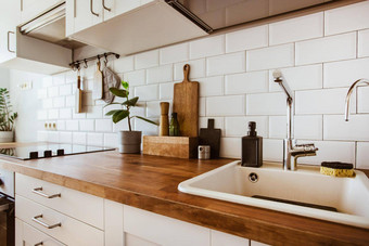 厨房<strong>黄铜</strong>餐具老板配件挂厨房白色瓷砖墙木桌面绿色植物厨房背景