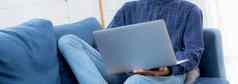 年轻的亚洲商人工作首页移动PC电脑在线互联网沙发生活房间自由男人。笔记本沙发上安慰正常的生活方式概念