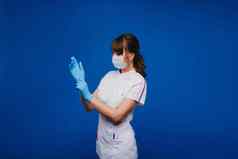 医生女孩站医疗面具孤立的蓝色的背景