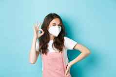 科维德健康流感大流行概念好年轻的支持女人穿医疗呼吸器显示标志批准赞美穿脸面具公共蓝色的背景