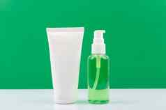 化妆品集脸奶油清洗泡沫透明的瓶白色表格绿色背景