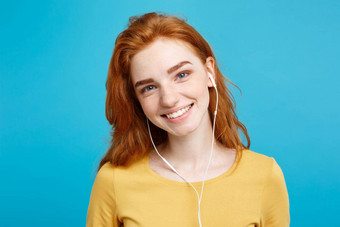 生活方式概念肖像快乐的快乐姜红色的头发女孩享受听音乐耳机快乐的微笑相机孤立的蓝色的柔和的背景复制空间