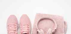 一对粉红色的纺织运动鞋无线耳机纺织粉红色的毛巾白色背景