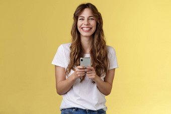 快乐的无忧无虑的快乐活泼的女孩持有智能手机太棒了有趣的应用程序玩很酷的游戏放松等待朋友公园浏览社会媒体移动电话相机乐观的微笑