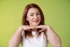 好快乐快乐的红色头发的人中年女人微笑很高兴持有手下巴接受缺陷有瑕疵的皮肤条件应用老化噪音化妆品绿色背景