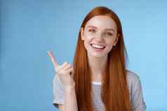 快乐有魅力的红色头发的人笑年轻的女孩有趣的无忧无虑的会说话的讨论产品出售指出指数手指显示复制空间广告站蓝色的背景