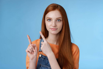自信的好看的红色头发的人女孩会说话的指出上左角落里指数手指显示自信地好产品推荐检查站蓝色的背景