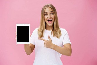 女人给建议买数字平板电脑指出设备屏幕指数手指微笑热情的很高兴告诉的意见小工具的绩效摆姿势很高兴粉红色的墙