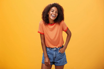 肖像有魅力的迷人的非洲美国时尚的非洲美国女时尚的短裤t恤笑幸福的享受会说话的很酷的人笑摆姿势橙色背景