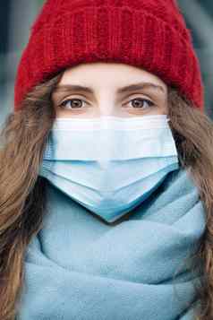 关闭肖像高加索人年轻的卷曲的女医疗面具站冬天城市人群人生病的科维德疫情冠状病毒流感大流行流感电晕病毒