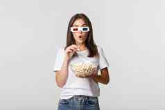 兴奋深刻的印象美丽的女孩吃爆米花看电影眼镜