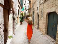 女人长橙色夏天衣服走狭窄的小巷燃烧室渗中世纪的历史小镇阿普利亚意大利