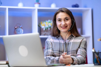 积极的迷人的女人工作首页微笑年轻的女人学生穿无线耳机移动PC学习在线教学互联网首页