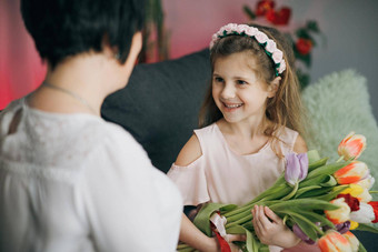 女儿祝贺上了年纪的妈妈。母亲的一天女孩拥抱妈妈快乐母亲的一天