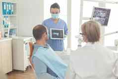 口腔学家护士显示牙x射线生病的病人解释治疗