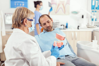 高级牙医女人持有牙科下巴骨架解释牙科手术