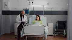 前面视图生病的女人休息床上讨论肿瘤学家男人。医生