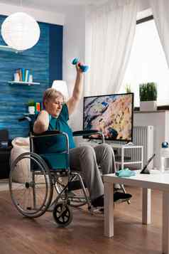 无效的高级女人轮椅看健身房身体锻炼平板电脑生活房间