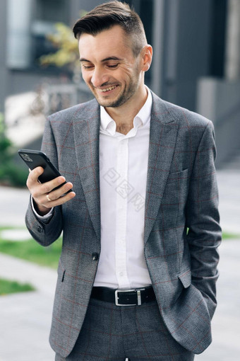 镜头英俊的有胡子的商人移动电话年轻的男人。发短信消息作弊智能手机业务中心垂直屏幕取向
