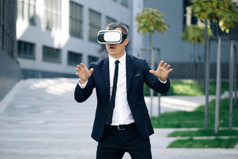 快乐商人玩游戏虚构的屏幕增强现实护目镜站背景现代城市建筑技术提供了维