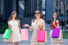 年轻的女孩色彩斑斓的购物袋走城市购物消费主义购买购物生活方式概念