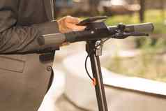 未知的商人经典西装未来电踏板车移动电话应用程序男人。租金电踏板车环保运输在户外业务中心