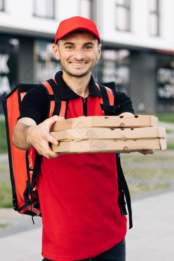 有吸引力的年轻的交付男人。<strong>快递</strong>红色的帽微笑相机持有披萨盒子交付快食物城市户外肖像城市工人概念<strong>快递</strong>首页交付披萨