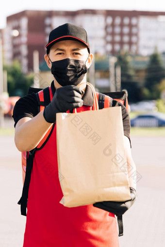 食物交付男人。持有纸袋食物街在户外<strong>首页</strong>送货人保护医疗脸面具手套冠状病毒科维德疫情检疫爆发交付服务