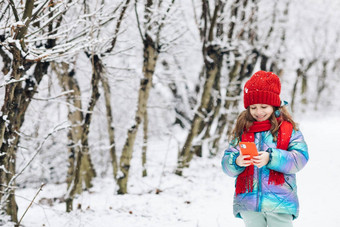 女孩滚动有趣的视频智能手机快乐孩子玩冬天森林智能手机屏幕细胞电话看漫画
