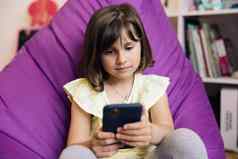 孩子智能手机孩子浏览互联网聪明的电话少年女孩沟通父母技术设备女孩移动电话闲谈，聊天