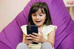 可爱的孩子女孩持有电话孩子智能手机孩子浏览互联网视频沟通首页电话