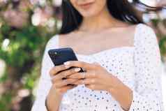 女人穿白色衣服智能手机女孩社会媒体应用程序文本消息收到新闻微笑户外沟通社会网络在线购物概念技术