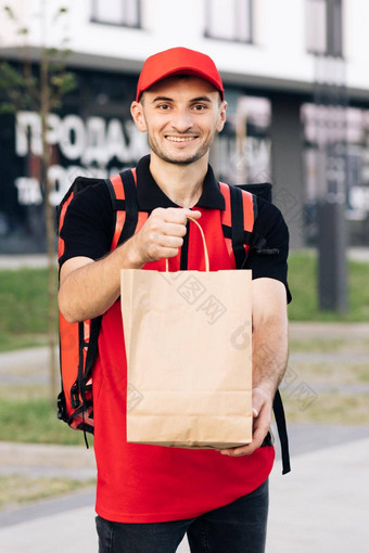 食物交付男人。订单餐厅英俊的年轻的男人。t恤帽快乐交付工人持有包食物微笑交付服务通过通过