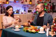 快乐的浪漫的夫妇吃圣诞节晚餐坐着餐厅表格