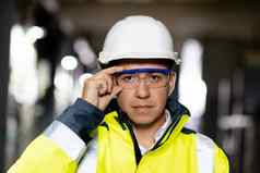 肖像员工亚洲男人。工程师工人穿安全统一的护目镜需要戴安全帽的相机网站工厂仓库背景