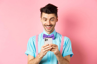 在线购物快乐的家伙智能<strong>手机屏幕</strong>阅读消息微笑站粉红色的背景