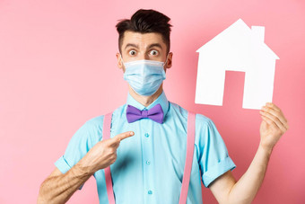 科维德流感大流行真正的房地产概念惊讶男人。脸面具指出纸房子断路站深刻的印象粉红色的背景
