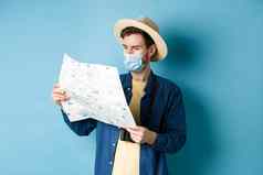 科维德流感大流行旅行概念英俊的年轻的的家伙脸面具夏天他旅游地图旅行假期站蓝色的背景