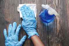 手蓝色的橡胶手套持有喷雾瓶清洁表格