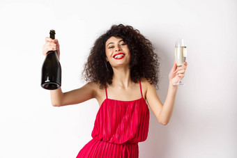 快乐聚会，派对女孩红色的衣服<strong>跳舞</strong>瓶香槟玻璃喝有趣的庆祝假期站白色背景