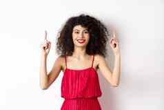 微笑女人优雅的红色的衣服化妆指出手指显示促销提供情人节一天站白色背景