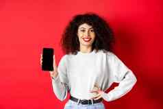 有吸引力的微笑女人显示空智能手机屏幕快乐广告在线商店应用程序站红色的背景