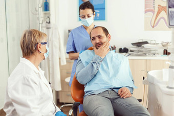 口腔学家医生会说话的男人。病人牙痛