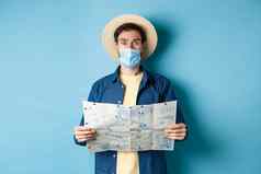 科维德流感大流行旅行概念旅游医疗面具惊讶持有地图站蓝色的背景