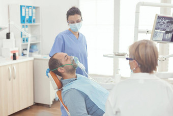 生病的病人坐着牙科椅子穿氧面具